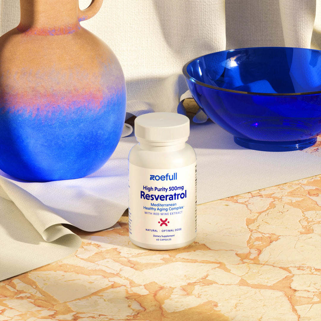 A lifestyle studio photo of zoefull's resveratrol supplement on a marble table and blue props.